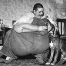 Portrait of Robert Earl Hughes (1926 - 1958), who was the world's heaviest man, as he pets the family dog, in Fishhook, IL, 1949