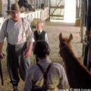 Boss Man (Jan Decleir, left) and his son (Nicholas Trueb, center) confront Richard (Chase Moore, foreground) after they learn he has stolen medicine from Boss Man's prized stallion, Caesar, to help Lucky (voiced by Lukas Haas) in Columbia's Runnin