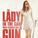 La dame dans l'auto avec des lunettes et un fusil