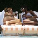 Larsa Pippen – With Kiki Barthlook in bikinis as they sit by the pool in Miami - 454 x 303