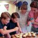 Kate's little helpers! Beaming Prince George, 8, Princess Charlotte, 7, and Prince Louis, 4, bake cakes with the Duchess of Cambridge for a Cardiff street party taking place today
